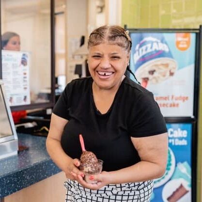 Woman holding a cup of chocolate ice cream with sprinkles.